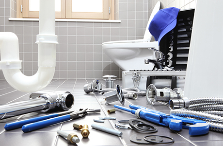 a bathroom with a variety of plumbing tools and toiletry parts strewn across the floor