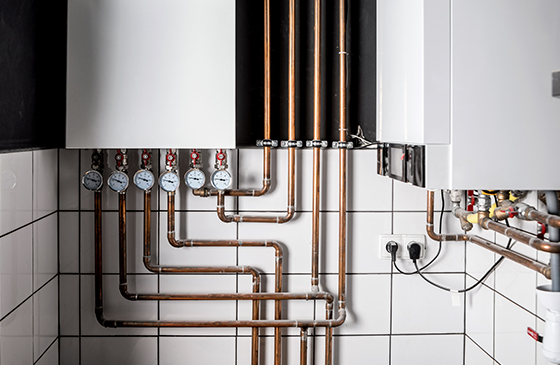 a number of copper pipes in a small room feeding water around a central heating system